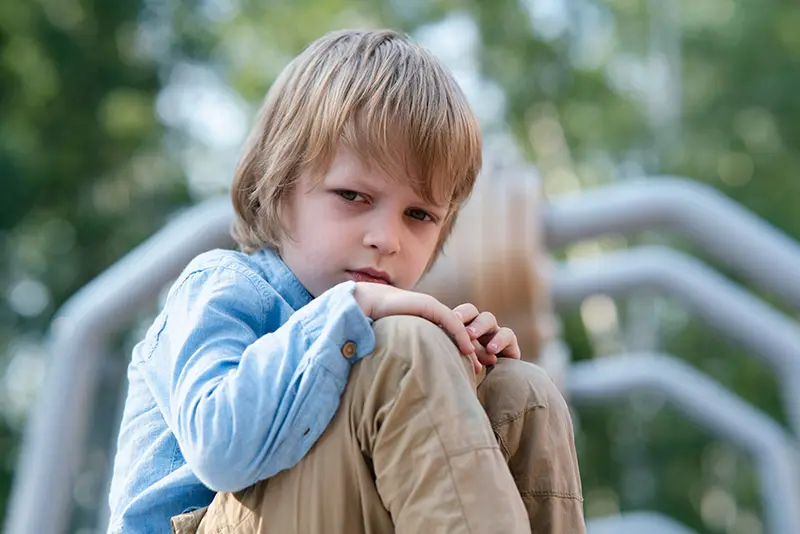 Sad young boy sitting alone